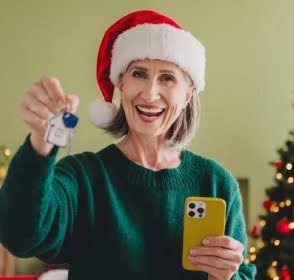 Mujer con gorro navideño y llaves de una vivienda