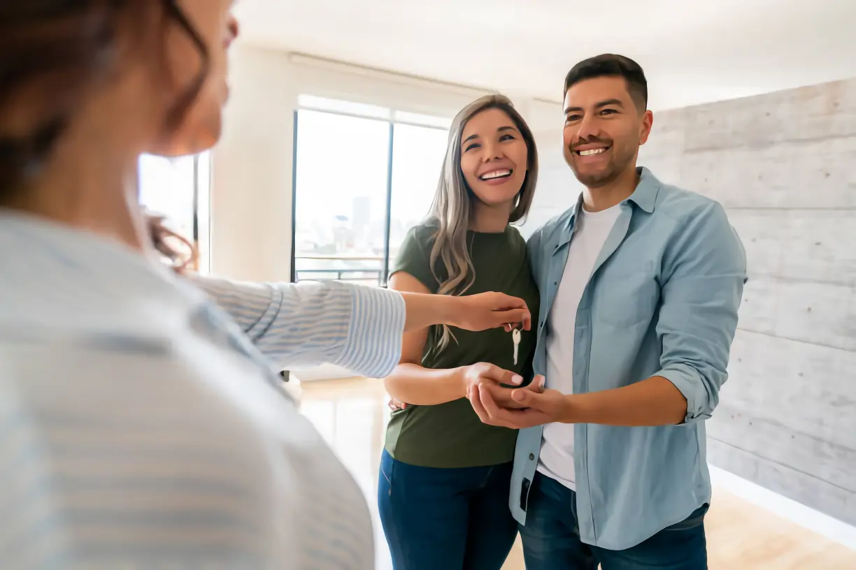 Pareja feliz recibiendo las llaves de su nueva vivienda
