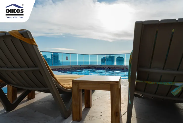 Zona de piscina y descanso con vista panorámica desde un proyecto residencial Piscina en la azotea con vista a la ciudad y zona de descanso con camillas